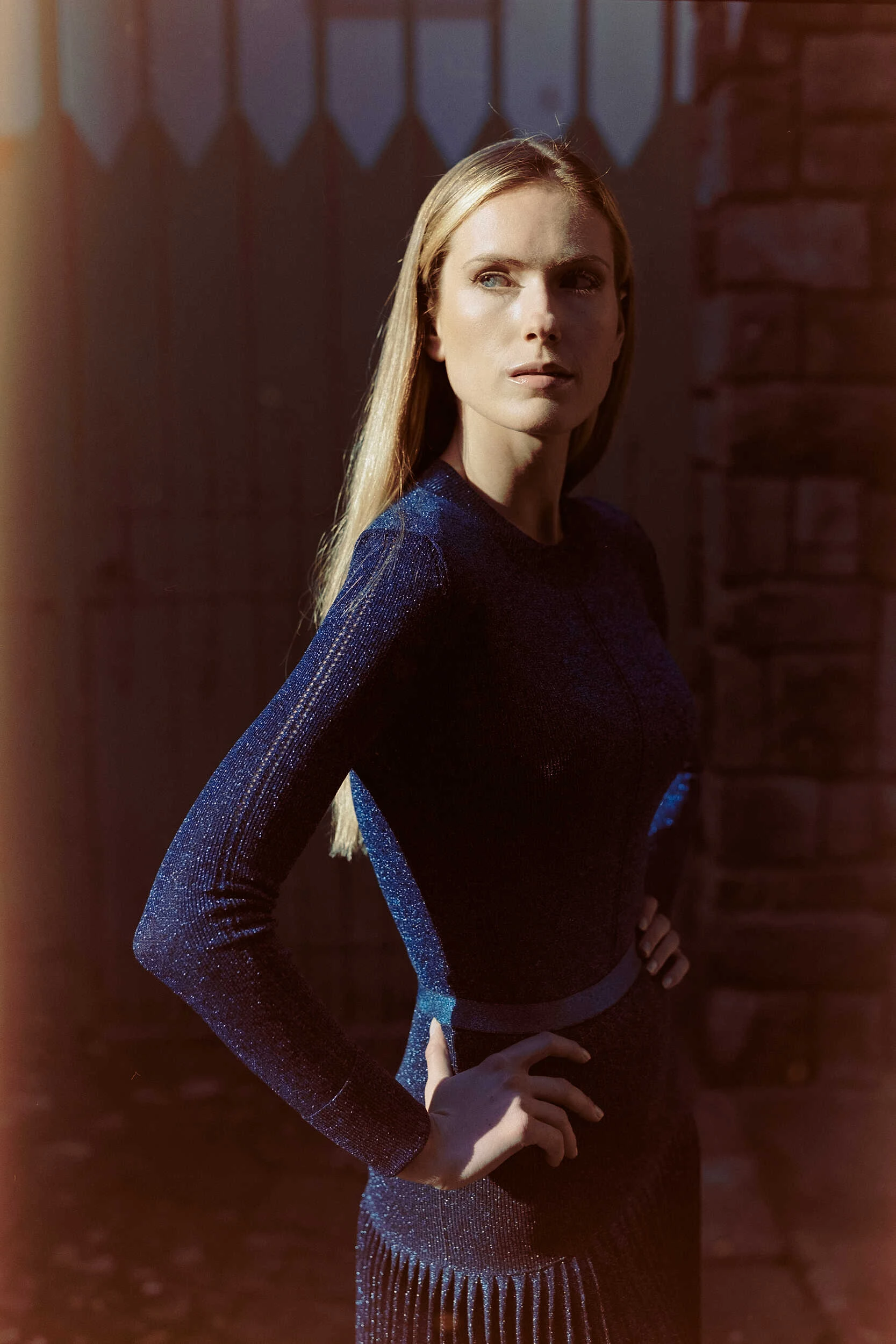 Blonde model in a navy knit outfit with a hand on the hip in Florence, hybrid photography