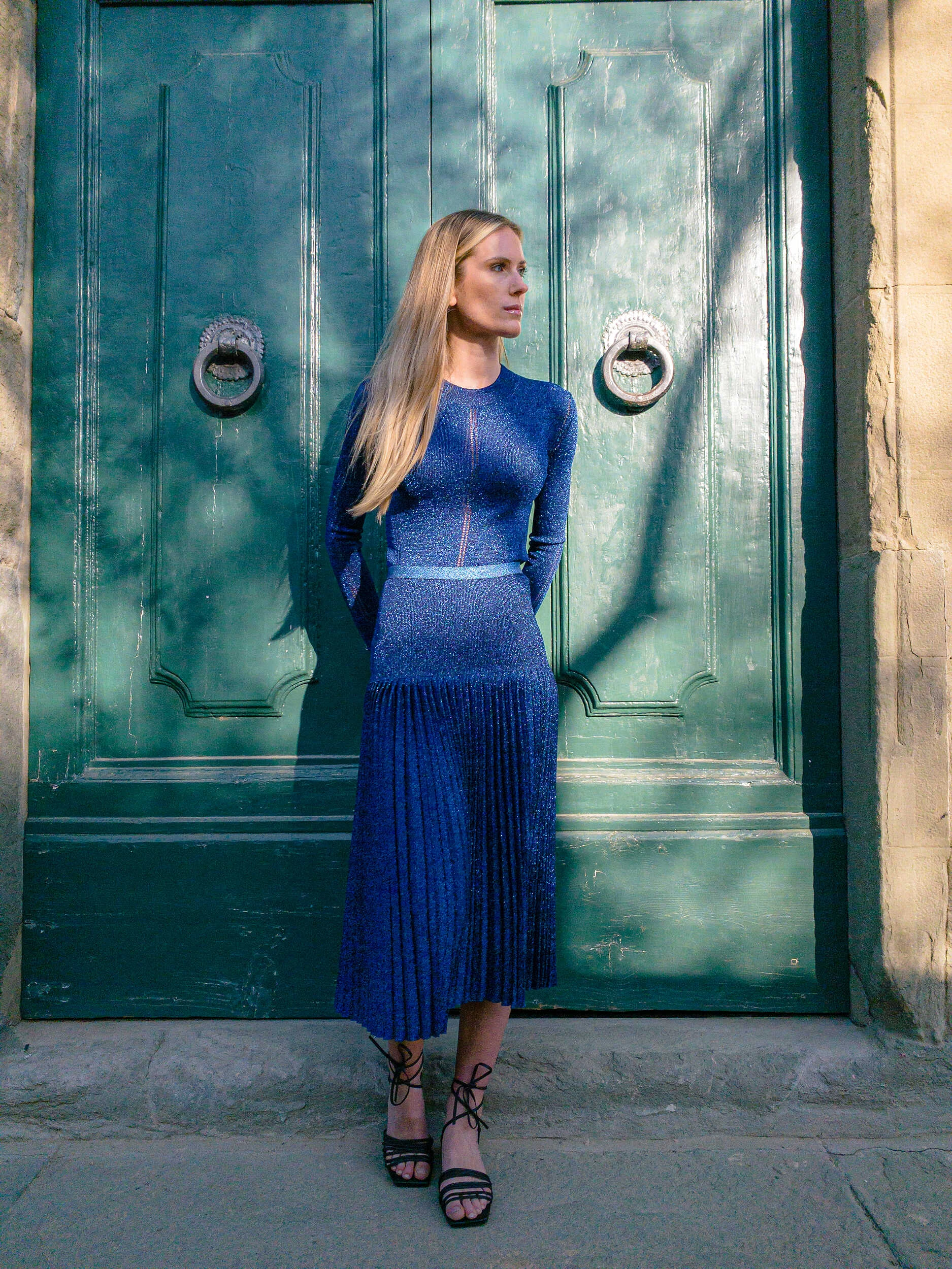 Blonde model in a navy knit dress against a green door in Florence, hybrid photography
