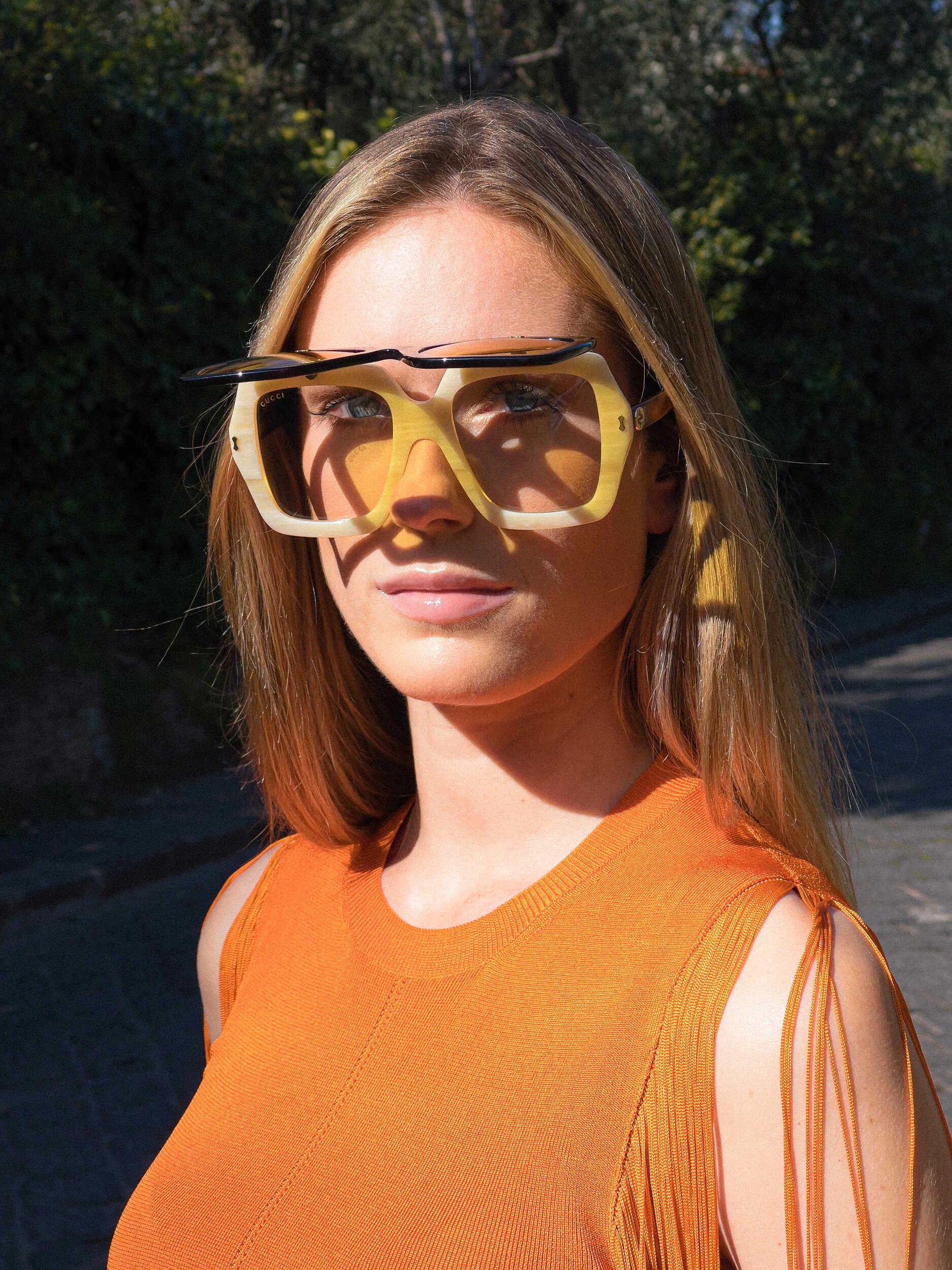 Close-up of a blonde model in an orange top and sunglasses in Florence, hybrid photography