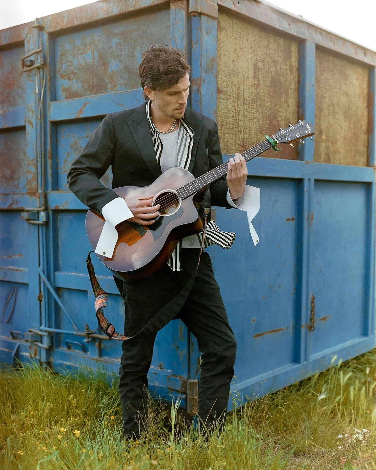 Robbie playing guitar against a blue container, shot on Fujifilm Pro 400H film