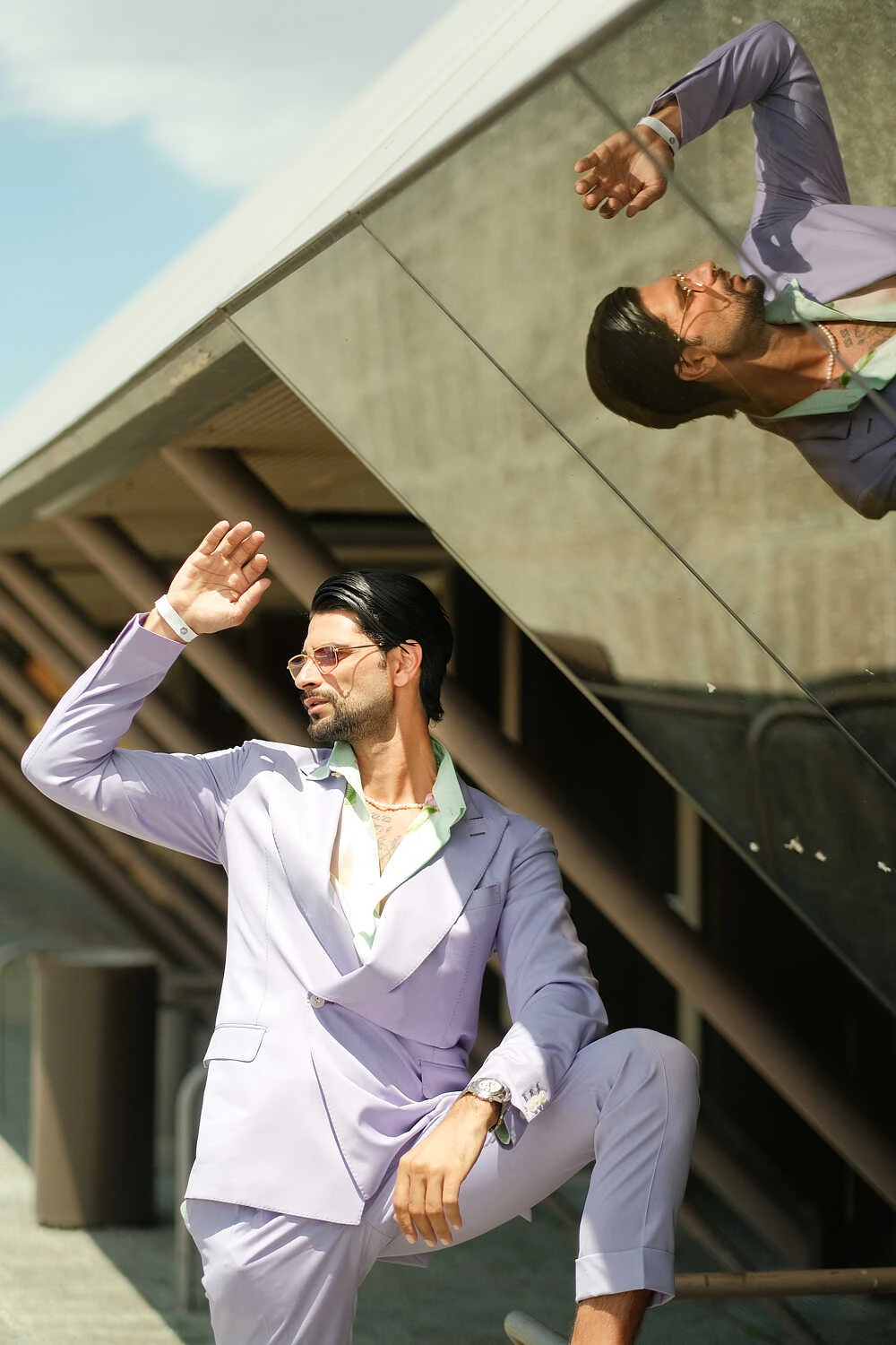 Man in a lilac suit leaning on a concrete structure, street style at Pitti Uomo 100 in Florence