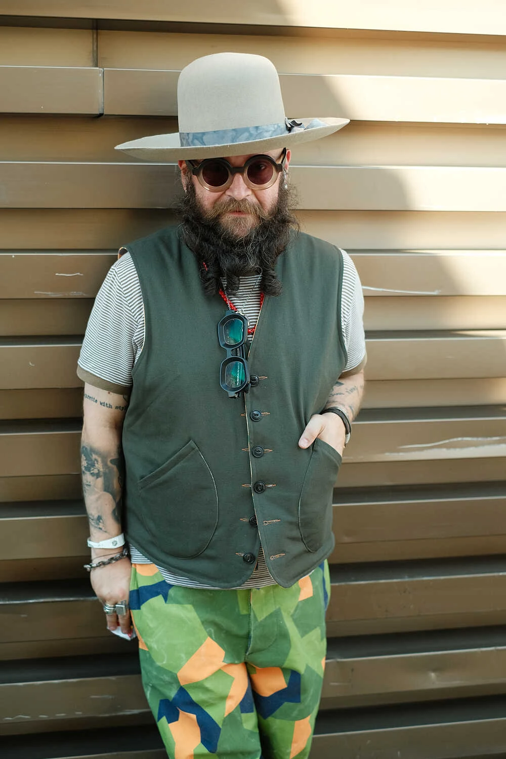 Man in a green vest and colourful trousers with a panama hat, street style at Pitti Uomo 100 in Florence
