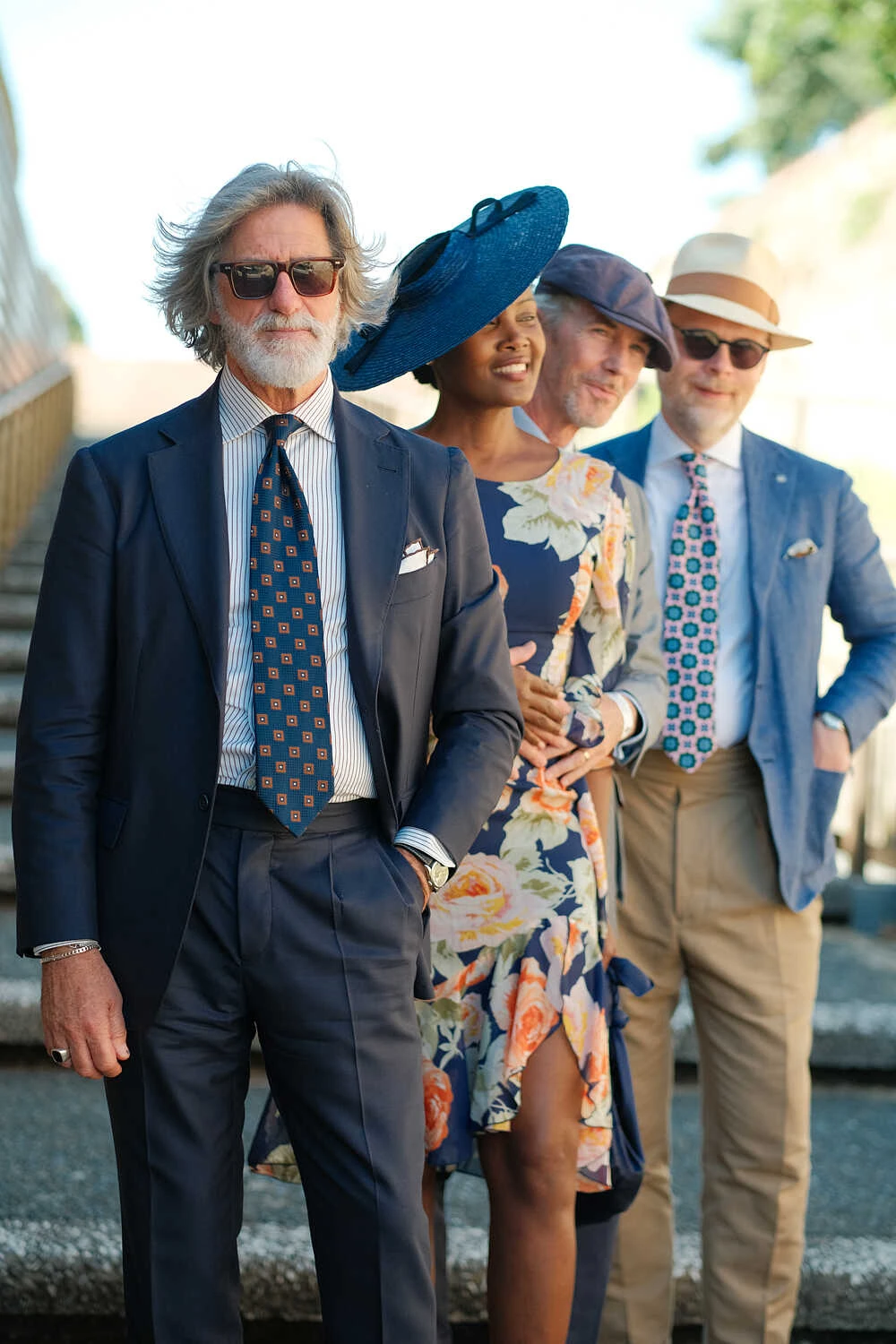 Group in navy suits and a floral dress, street style at Pitti Uomo 100 in Florence