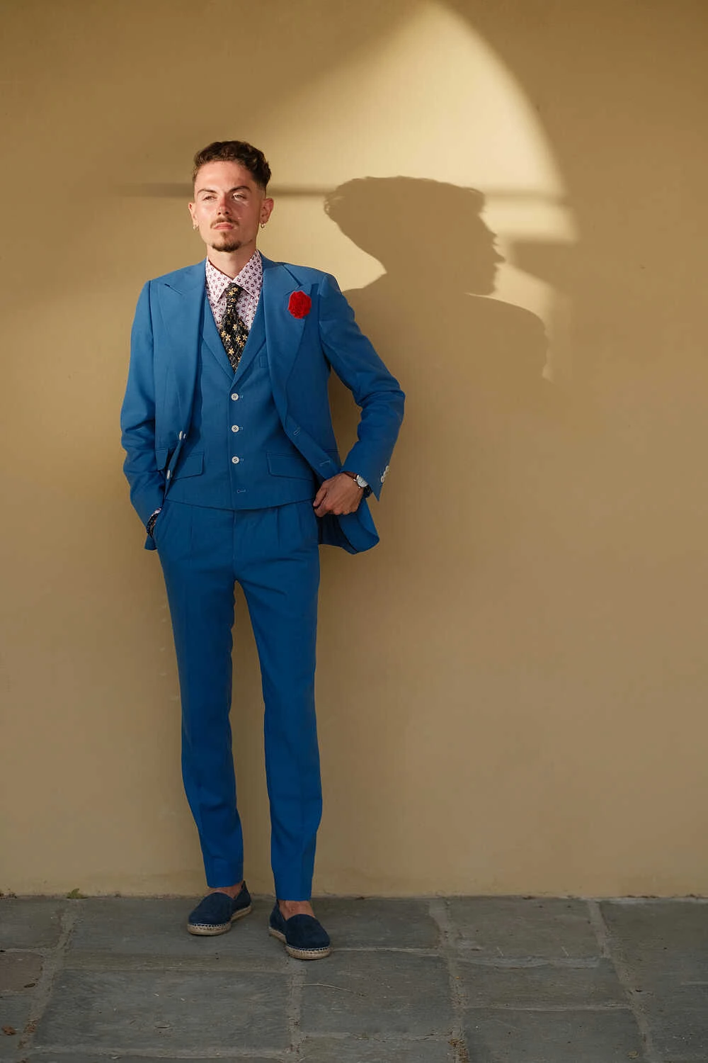 Model in a blue three-piece suit against an ochre wall for Hockerty in Florence