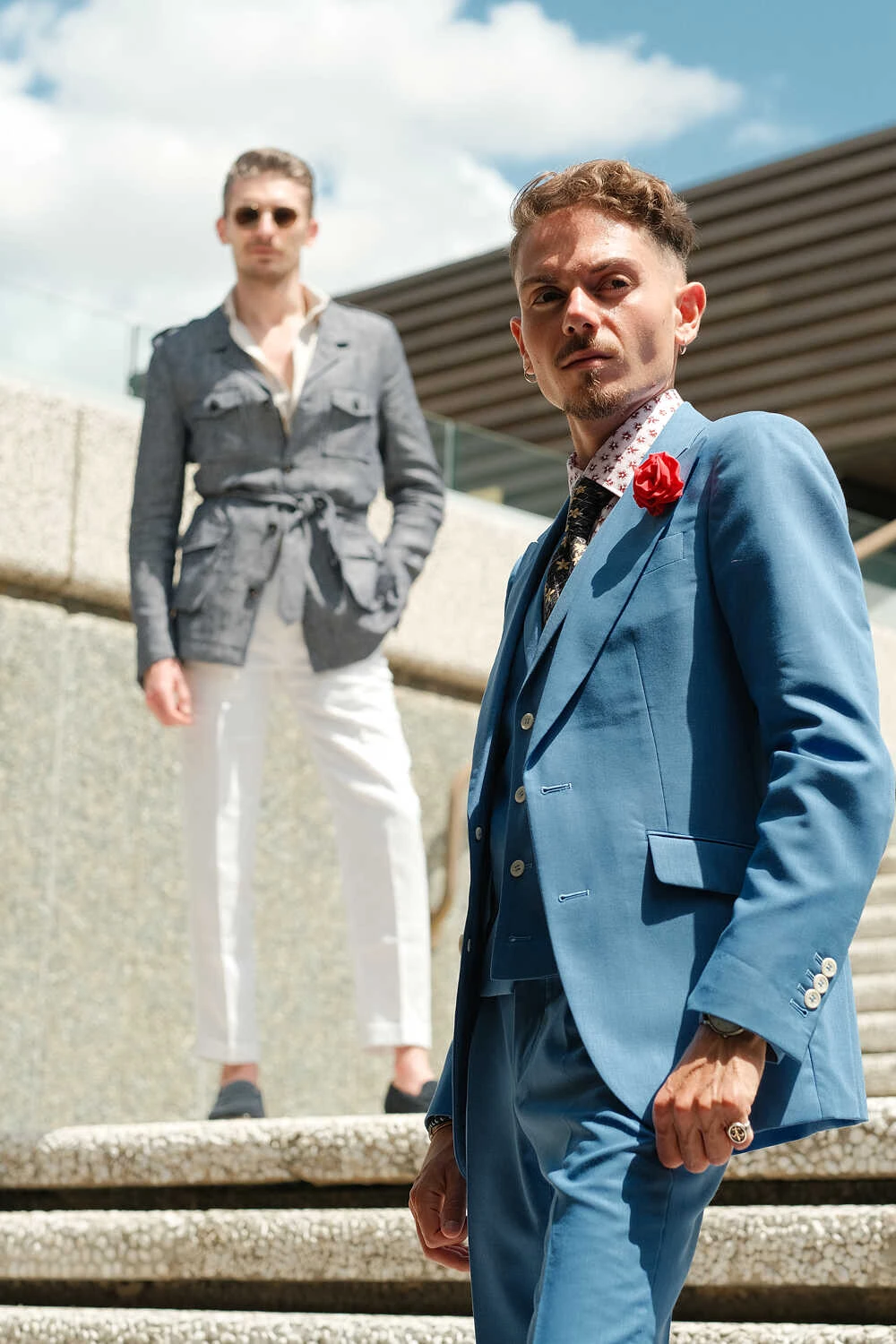 Two models in a grey jacket and blue suit on stairs for Hockerty in Florence