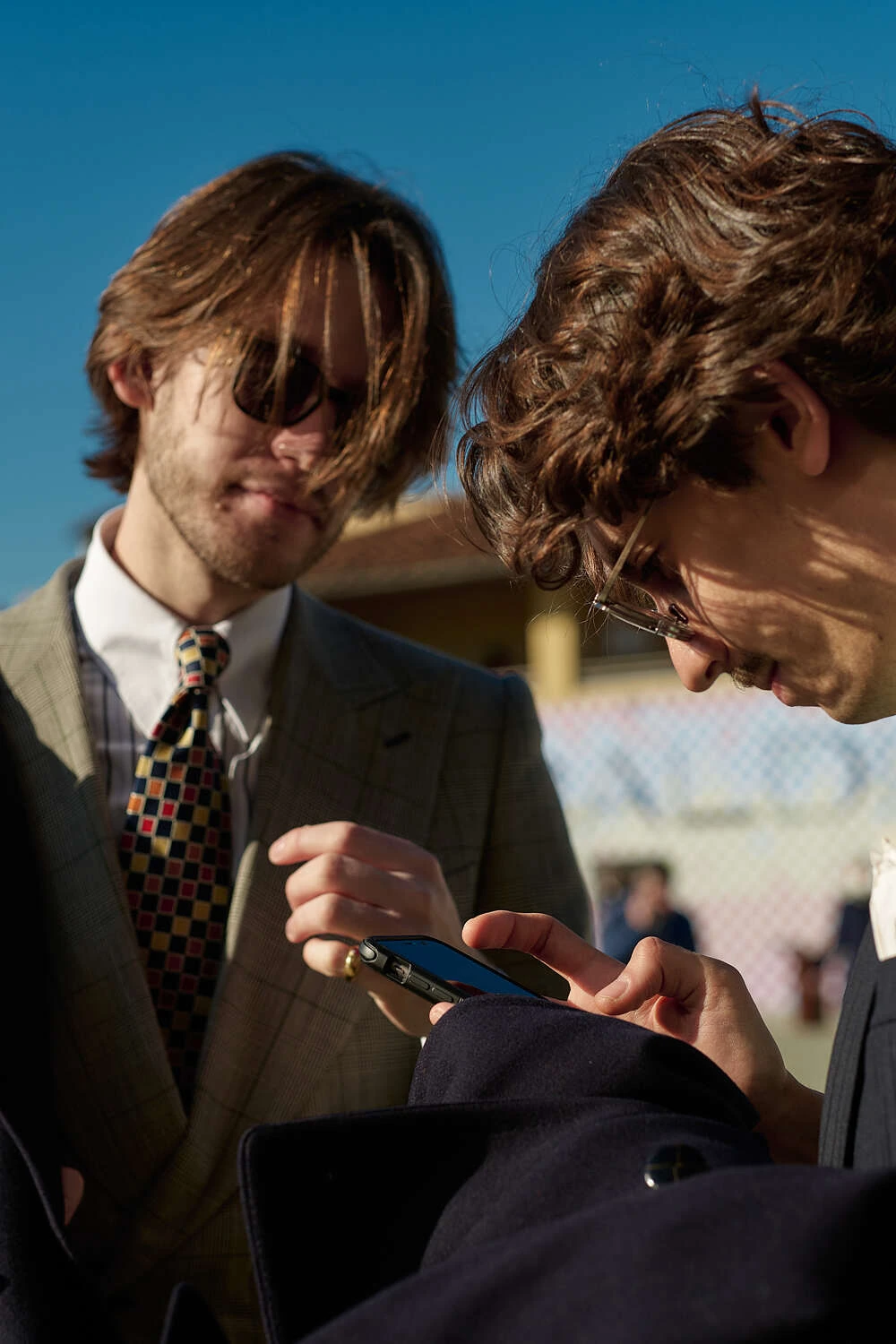 Two young men in tweed suits looking at a phone, street style at Pitti Uomo 101 in Florence