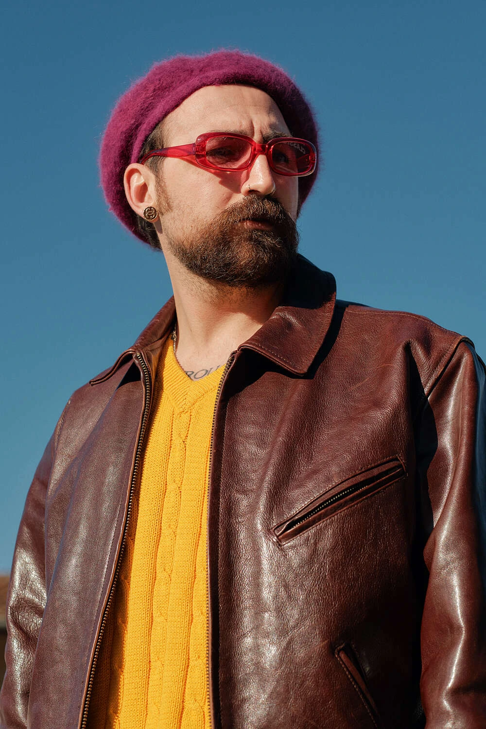 Man in a burgundy beret and brown leather jacket over a yellow sweater, street style at Pitti Uomo 101 in Florence