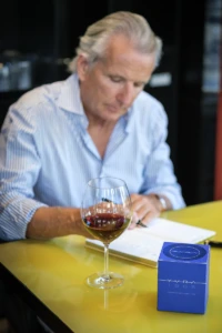 Man writing at a table with cognac-coloured perfume and a blue YVRA box in Amsterdam