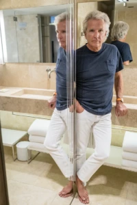 Man in a navy tee leaning by a bathroom mirror at the Conservatorium Hotel in Amsterdam, YVRA shoot