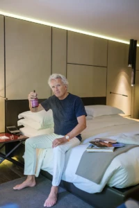 Man spraying YVRA perfume on a hotel bed at the Conservatorium Hotel in Amsterdam