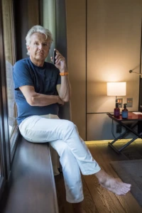 Man seated on a windowsill in a navy tee in Amsterdam, YVRA perfume shoot