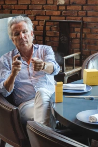 Man spraying YVRA perfume toward the camera in a brick interior in Amsterdam