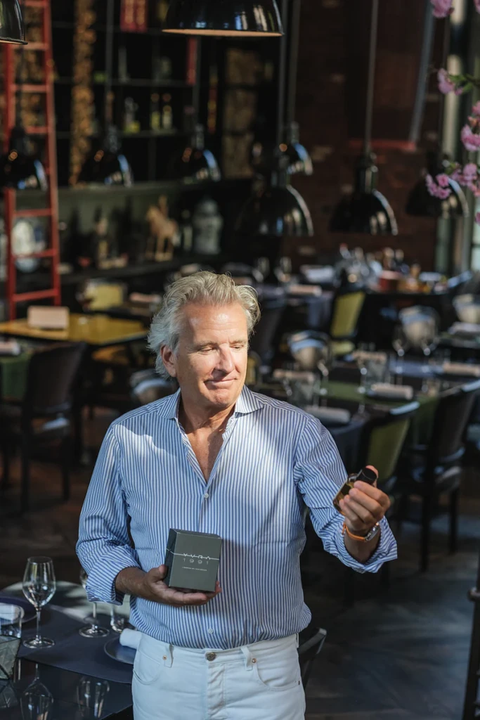Man holding a YVRA perfume box in the Conservatorium Hotel restaurant in Amsterdam