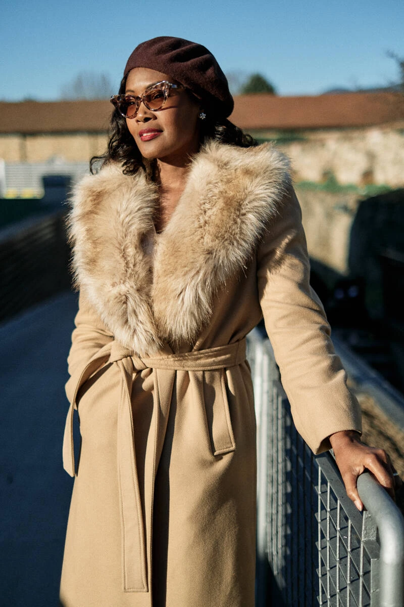 Woman in a camel coat with fur collar and brown beret, street style at Pitti Uomo 103 in Florence