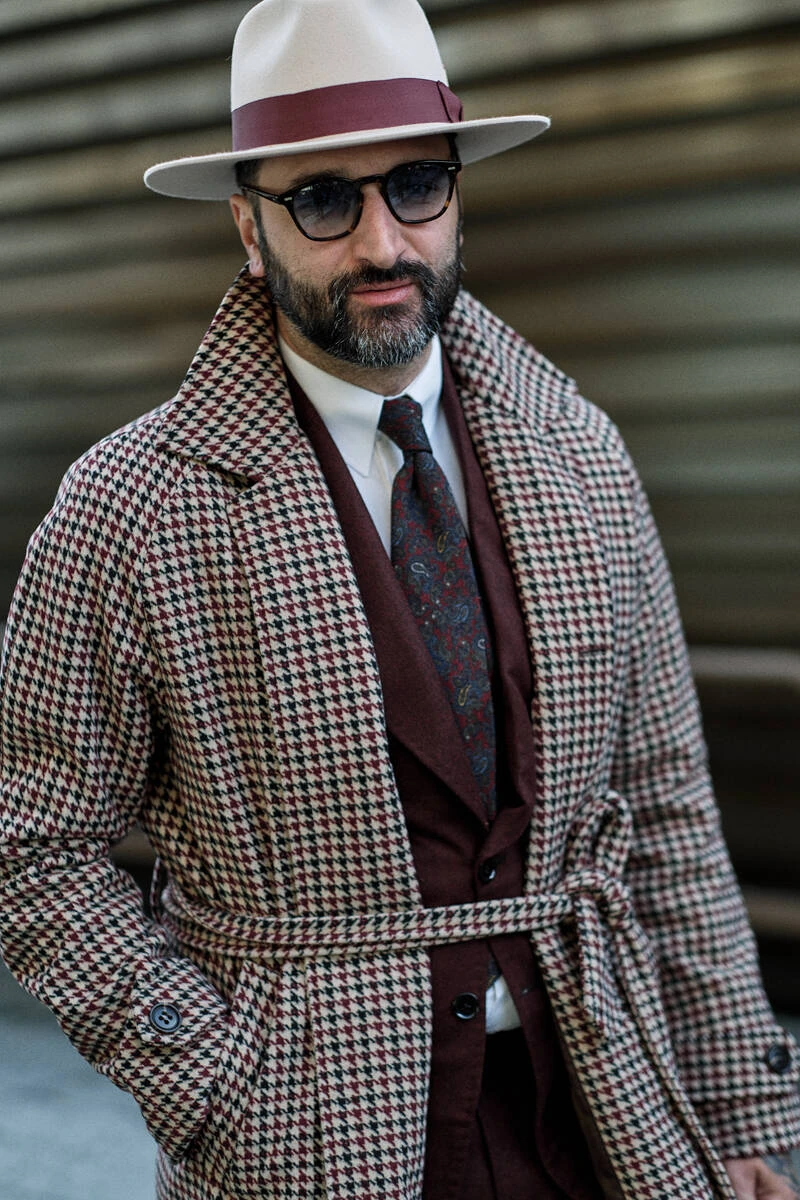 Man in a houndstooth suit and straw hat, street style at Pitti Uomo 103 in Florence