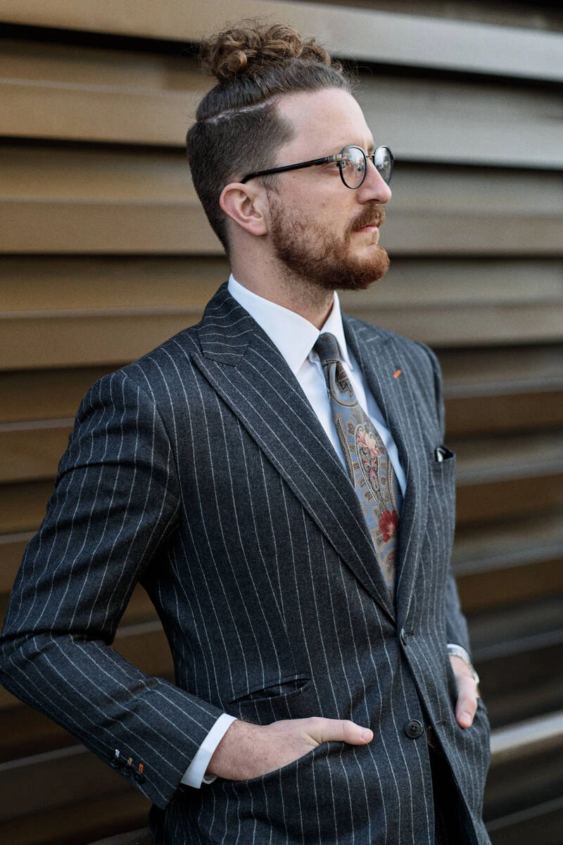 Man in a grey pinstripe suit with a patterned tie, street style at Pitti Uomo 103 in Florence