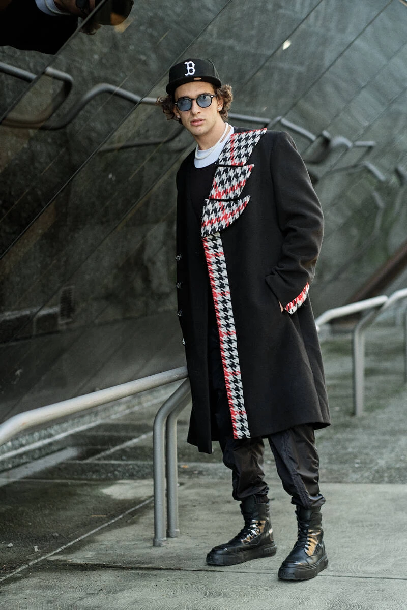 Man in a long black coat with houndstooth scarf, street style at Pitti Uomo 103 in Florence