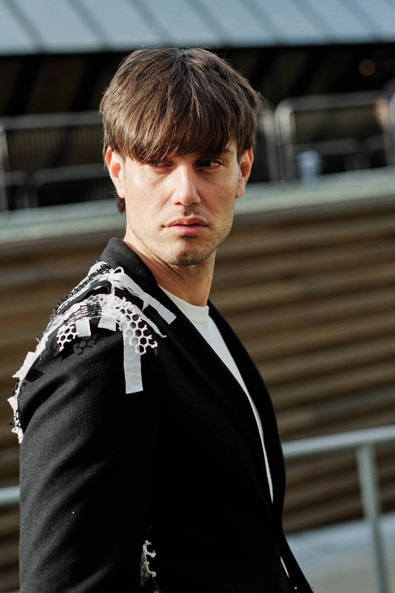 Man in a black blazer with a beaded shoulder, street style at Pitti Uomo 103 in Florence