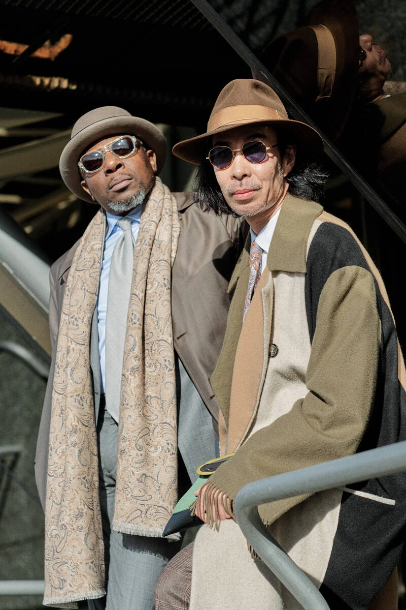 Two men in overcoats and fedoras on stairs, street style at Pitti Uomo 103 in Florence