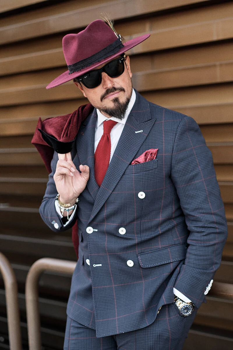 Man in a grey checked suit with a burgundy hat and scarf, street style at Pitti Uomo 103 in Florence
