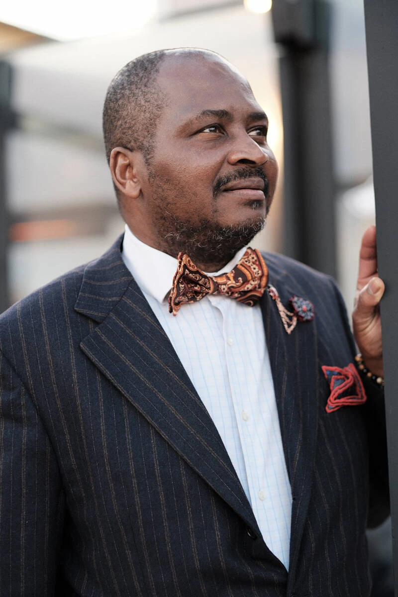 Man in a navy pinstripe suit with a patterned bow tie, street style at Pitti Uomo 103 in Florence