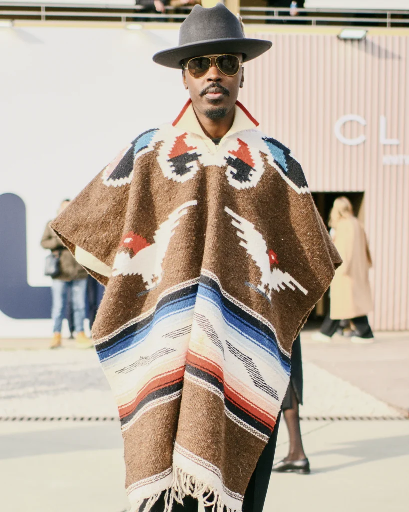 Man in a patterned wool poncho and grey fedora, street style at Pitti Uomo 105 in Florence