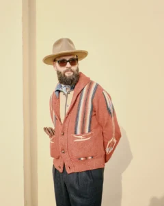 Bearded man in a terracotta striped cardigan and tan hat, street style at Pitti Uomo 105 in Florence