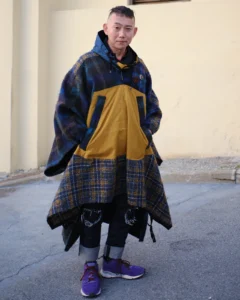 Man in an oversized tartan and mustard patchwork coat with purple sneakers, street style at Pitti Uomo 105 in Florence