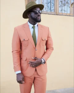 Man in a coral suit with a green tie and olive hat, street style at Pitti Uomo 105 in Florence