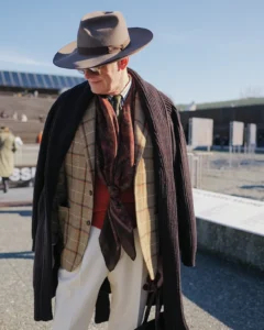 Older man in a layered brown overcoat and checked tweed with a fedora, street style at Pitti Uomo 105 in Florence