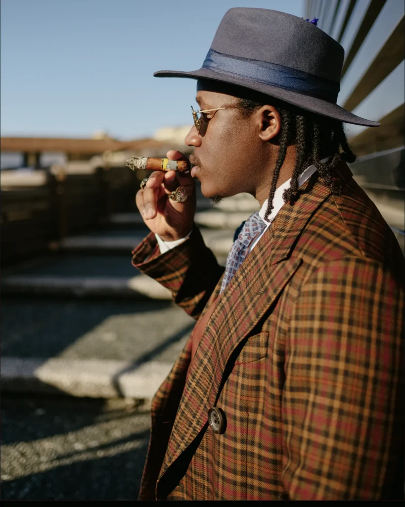 Man in a brown plaid tweed jacket and grey fedora, street style at Pitti Uomo 105 in Florence