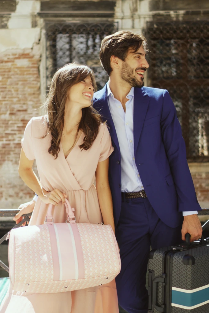 Model duo posing with a Vonto pink weekender bag and hard-shell rolling luggage outside a Venetian palazzo