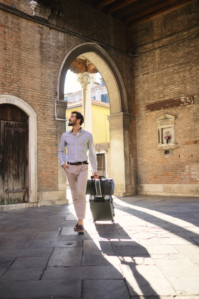 Man walking through a Venetian arcade with a Vonto graphite hard-shell rolling suitcase
