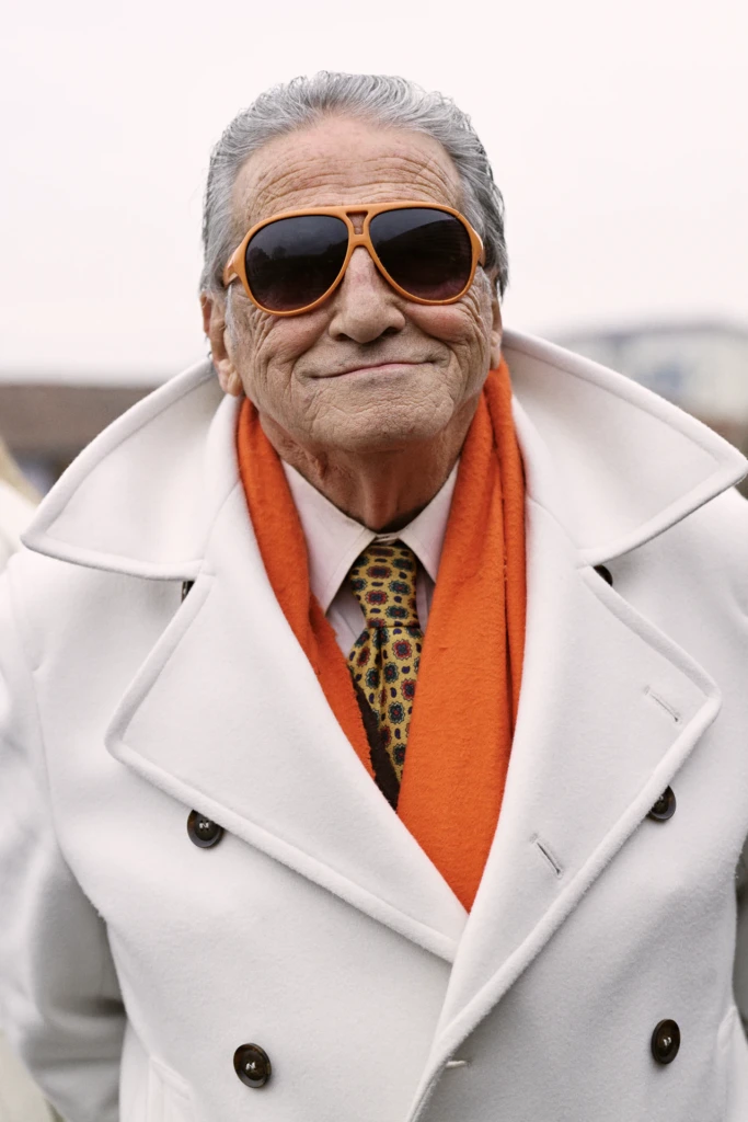 Elderly man in a white overcoat with an orange scarf and orange aviator sunglasses, Pitti Immagine Uomo 109 fair, Florence