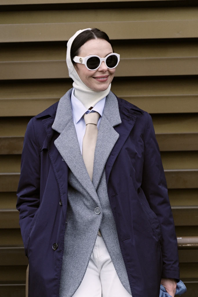Woman in a white knit hood and navy trench coat over a grey herringbone blazer, Pitti Immagine Uomo 109 fair, Florence