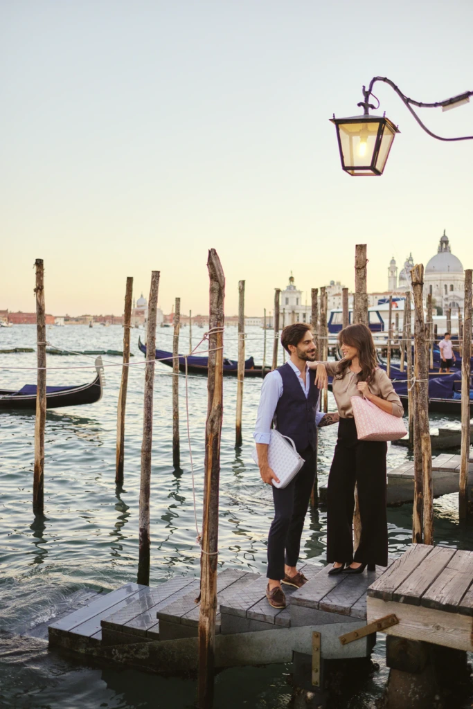 Golden-hour couple on a Venice pier with a Vonto leather clutch, San Giorgio Maggiore in the background
