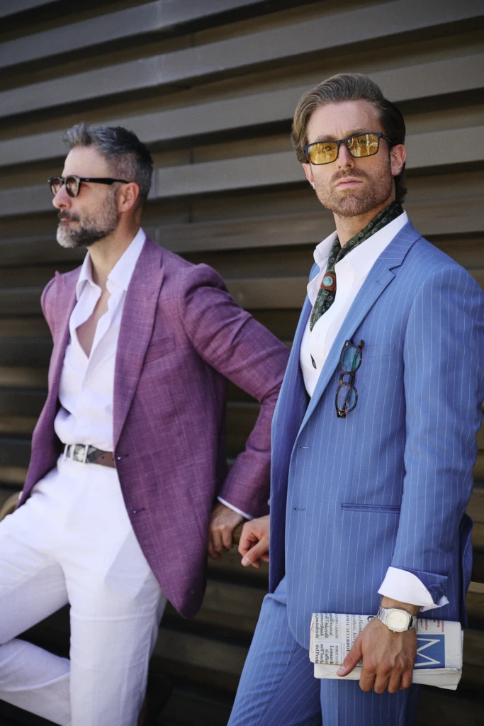Two men in pastel suits, one in lilac and one in mint, both wearing sunglasses