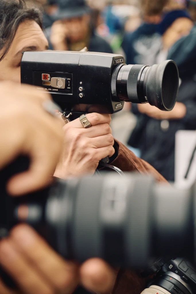 Close-up of a hand holding a vintage Yashica Super-8 Electro film camera, filming the crowd at Milano Fashion Week