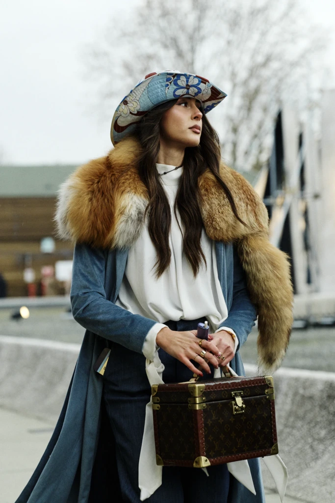 Woman in a floral quilted cap and fox fur stole holding a vintage Louis Vuitton vanity trunk, another frame, Pitti Immagine Uomo 109 fair