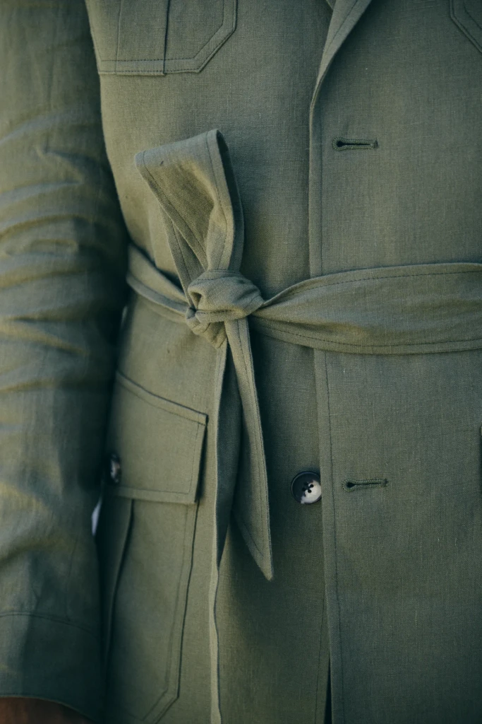Close-up of an olive green belted jacket with a tied waist knot