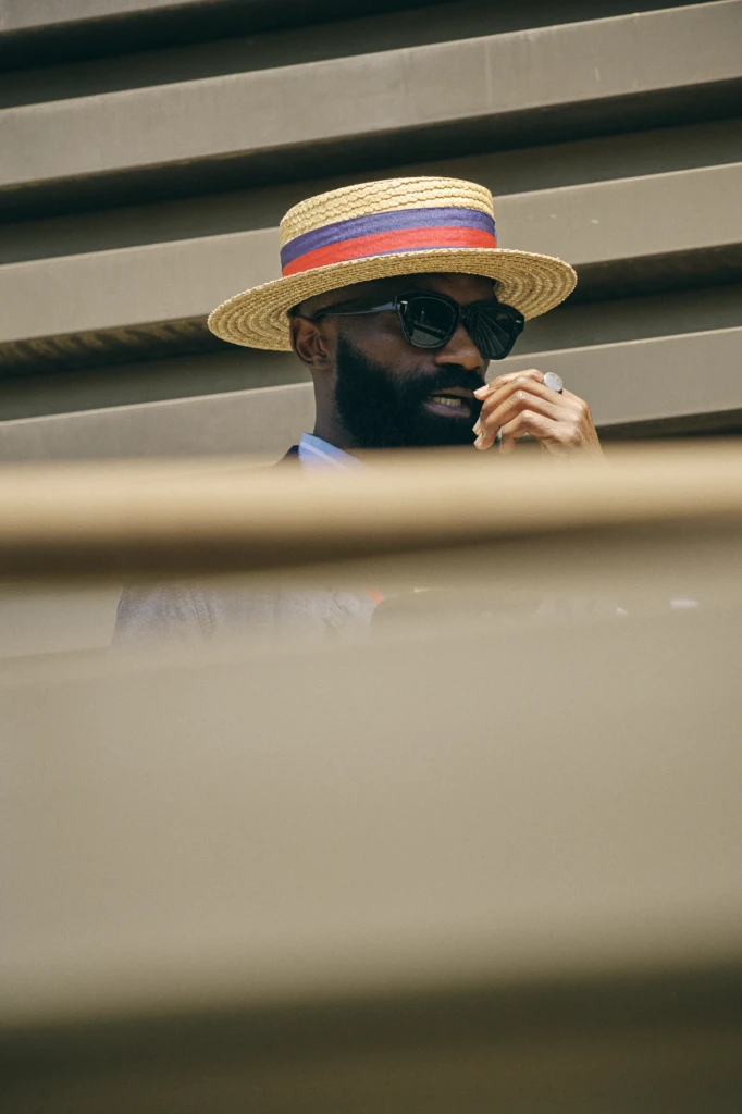 Man in a straw boater hat with a red and blue striped band, wearing sunglasses