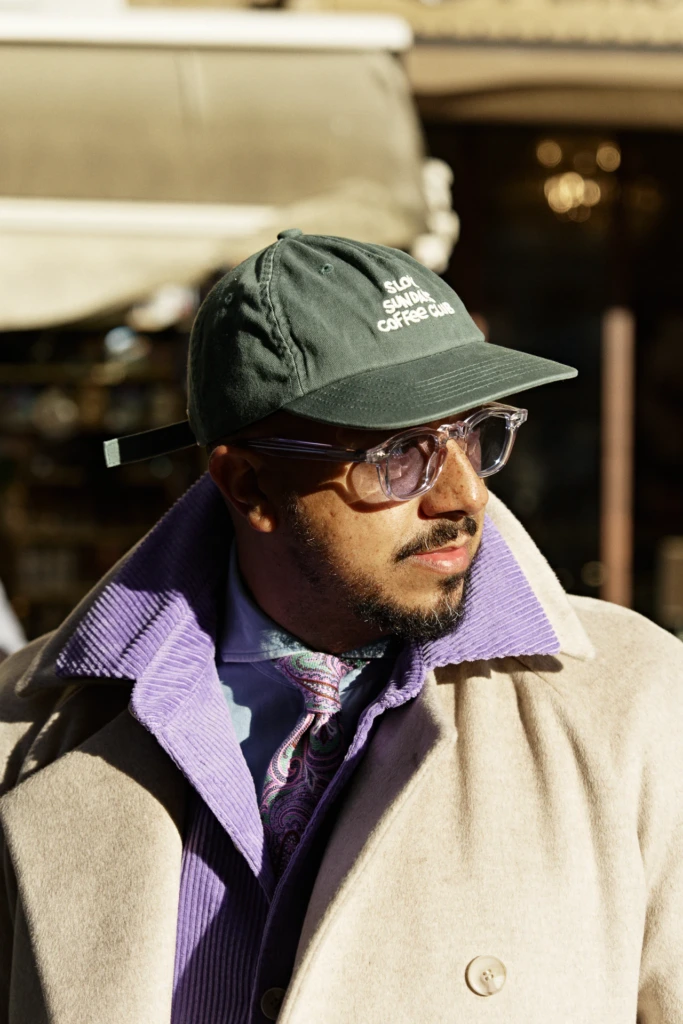Neto, Pedro and Carlos editorial in Florence — close portrait in a cream wool overcoat, purple corduroy collar and paisley tie during Pitti Immagine Uomo 107.