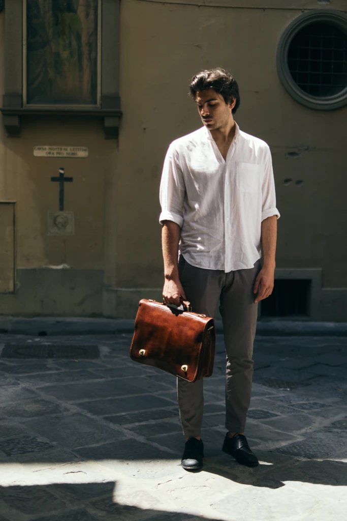 tan leather briefcase bag carried through a sunlit Florence street