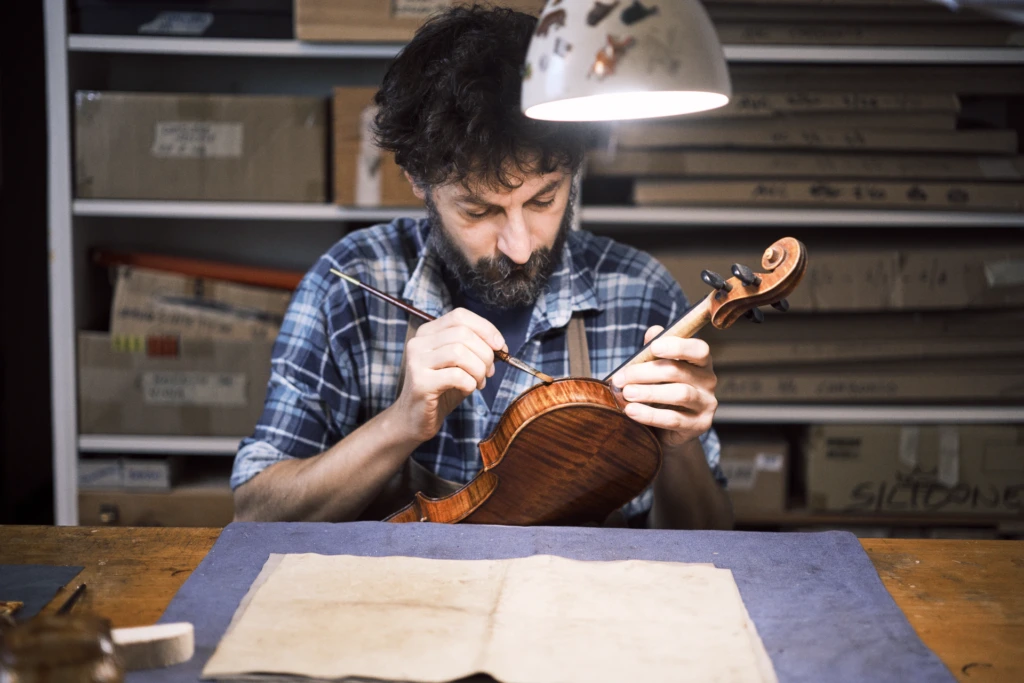 Master luthier shaping a violin body in his Florence atelier