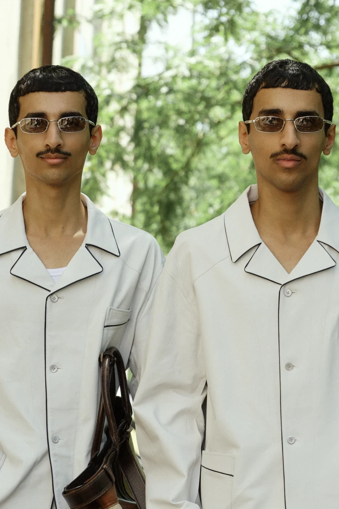 Twin-look street style portrait of two men in matching light suits and rectangular sunglasses, Milano Fashion Week