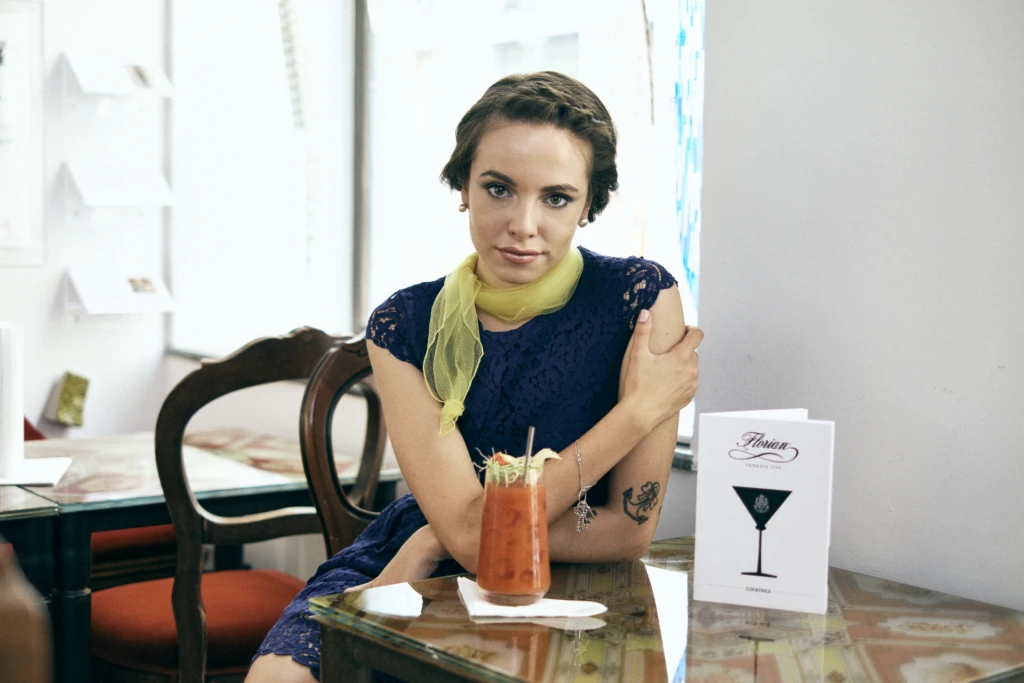 Woman in a navy lace dress with a cocktail at Caffè Florian, Venice